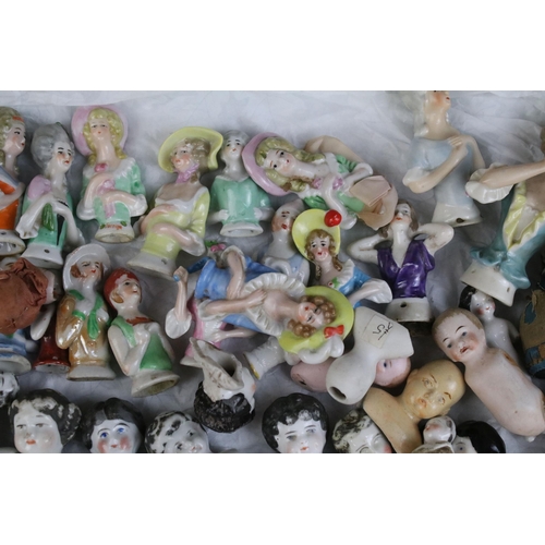 139 - A large collection of antique ceramic pin cushion dolls and doll heads of various sizes and styles.