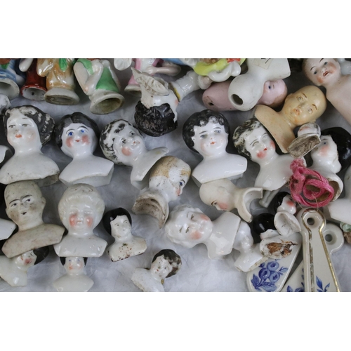 139 - A large collection of antique ceramic pin cushion dolls and doll heads of various sizes and styles.