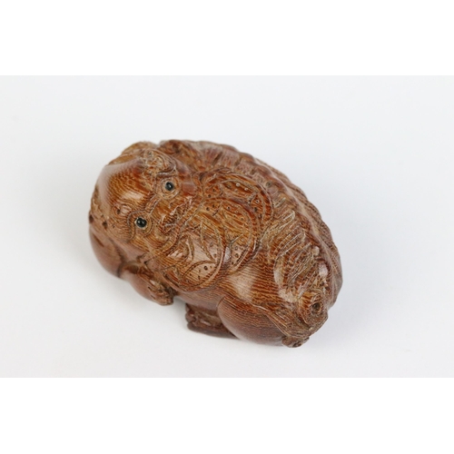 101 - Two carved wooden netsuke figures of a Chinese dragon to include one eating fruit