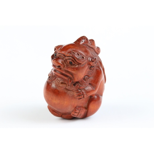 122 - Two carved wooden netsuke figures of Chinese dragons, one holding a large ball signed