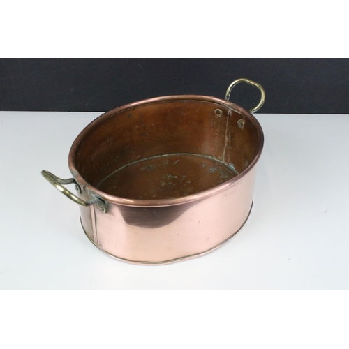 96 - Copper oval pot or planter with rolled rim and twin brass loop handles, 34cm long