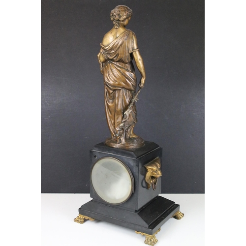 98 - Cast metal lady with bird sculpture atop a black marble mantle clock base with ogre head side handle... 