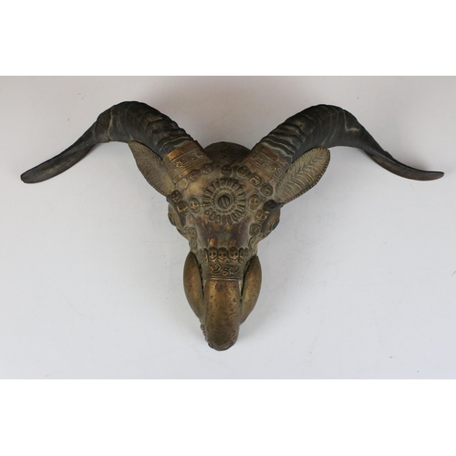 135 - Horned goat skull ornamented with metal applique and skull detail, W 27cm