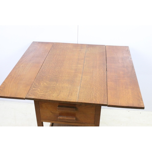 587 - Stanley Webb Davies 1946 oak drop leaf table with side drawers and lower shelf set on castors, H 73c... 