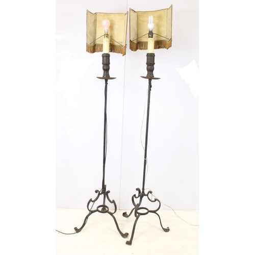 612 - Pair of wrought iron scroll tripod base floor lamps with old deed type fringed lamp shades, H 176cm