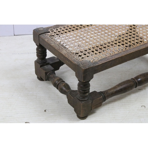 586 - Antique Jacobean style cane top wood carved footstool, H 23cm, W 55cm, D 34cm