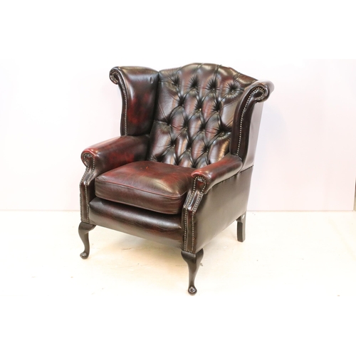 613 - Oxblood leather chesterfield wing back arm chair having button back seat with cabriole legs. Measure... 