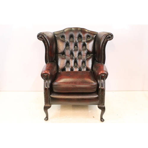 613 - Oxblood leather chesterfield wing back arm chair having button back seat with cabriole legs. Measure... 