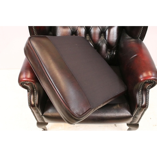 613 - Oxblood leather chesterfield wing back arm chair having button back seat with cabriole legs. Measure... 