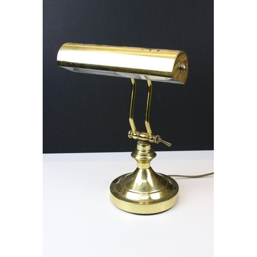 104 - Brass bankers lamp with adjustable cylinder shade raised on a round plinth base. Measures 31cm tall.... 