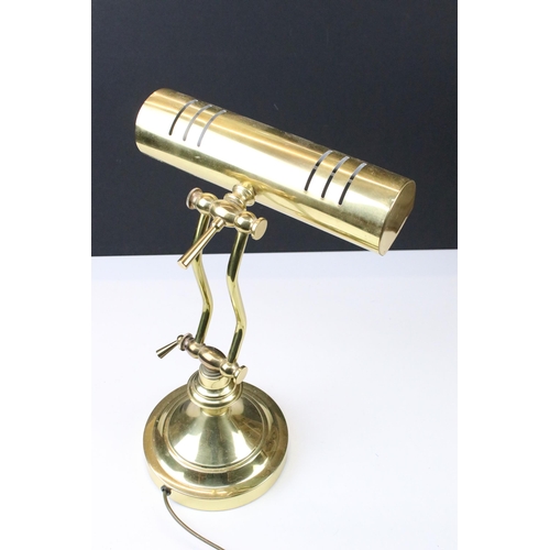 104 - Brass bankers lamp with adjustable cylinder shade raised on a round plinth base. Measures 31cm tall.... 