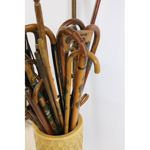 122 - large ceramic umbrella stick stand together with a large quantity of walking sticks in varying forms... 