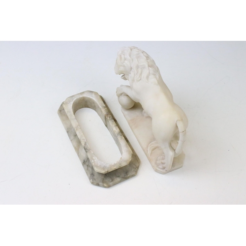 127 - Carved marble lion with one raised paw, raised on a plinth base. Measures 17cm wide.