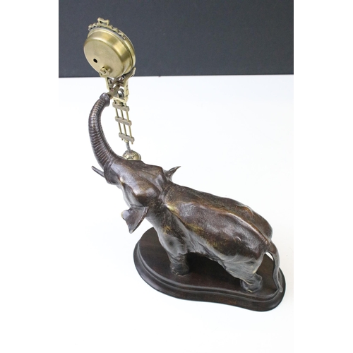 130 - Novelty elephant clock having a cast metal elephant on wooden base with swinging clock to the raised... 