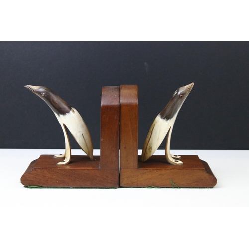 133 - Art Deco mahogany bookends, each set with a horn penguin, 15cm