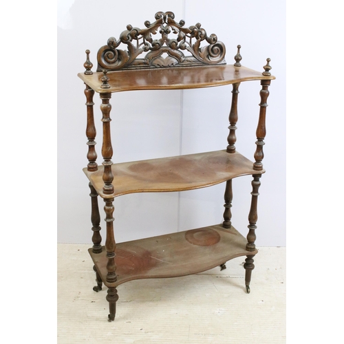 635 - Late 19th / early 20th century mahogany three tier whatnot, with intricately carved pediment, above ... 