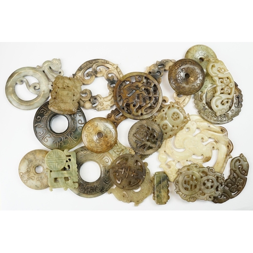 210 - A collection of twenty three oriental carved jade and stone amulets of traditional form.