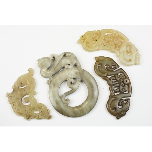 210 - A collection of twenty three oriental carved jade and stone amulets of traditional form.