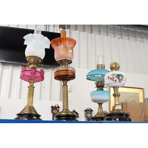 333 - Group of four early 20th century oil lamps to include opaque coloured glass, coloured glass and whit... 