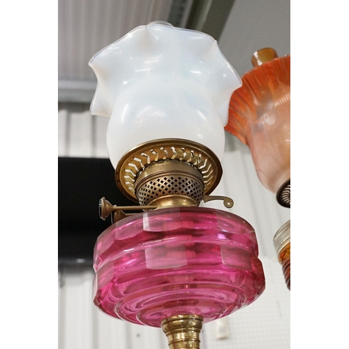 333 - Group of four early 20th century oil lamps to include opaque coloured glass, coloured glass and whit... 