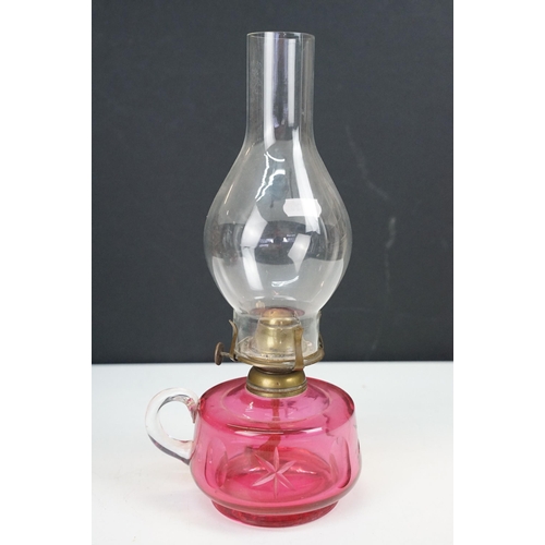 36 - Collection of Victorian oil lamps to include two large cranberry glass and clear chimney examples, t... 