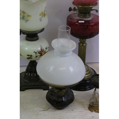 430 - Group of four Victorian oil lamps to include cranberry glass, brass based, white glass shade and flo... 