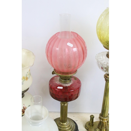 430 - Group of four Victorian oil lamps to include cranberry glass, brass based, white glass shade and flo... 