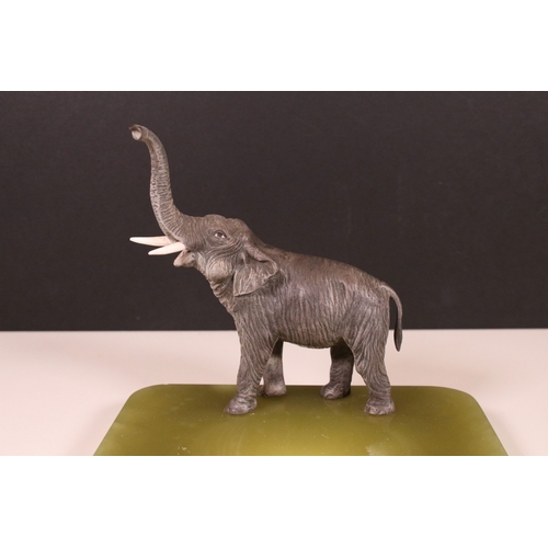 192 - Cold painted bronze elephant with raised trunk stood on an onyx dish base, H 16cm, W 18cm, D 16cm