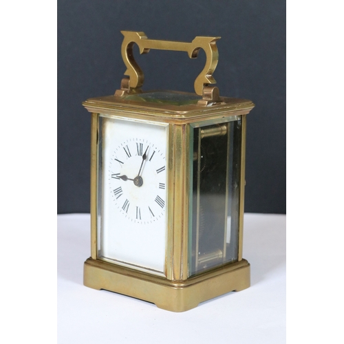 257 - An early 20th century brass cased carriage clock with beveled glass panels and white enamel dial.