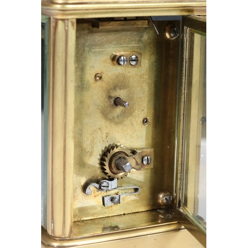 257 - An early 20th century brass cased carriage clock with beveled glass panels and white enamel dial.