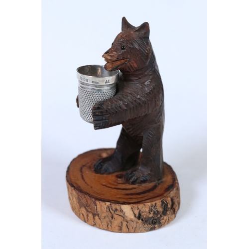 313 - A small black forest bear thimble holder complete with hallmarked silver thimble and scissors.