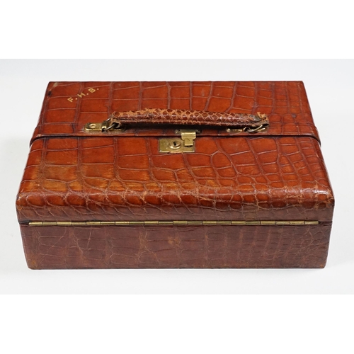 366 - A vintage Crocodile skin jewellery box, green velvet fitted interior with brass fittings.