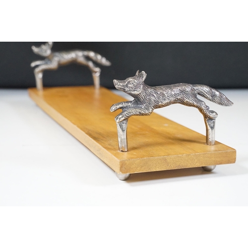 152 - Wooden bookstand with cast metal supports in the form of running foxes, on four ball feet, 44cm long