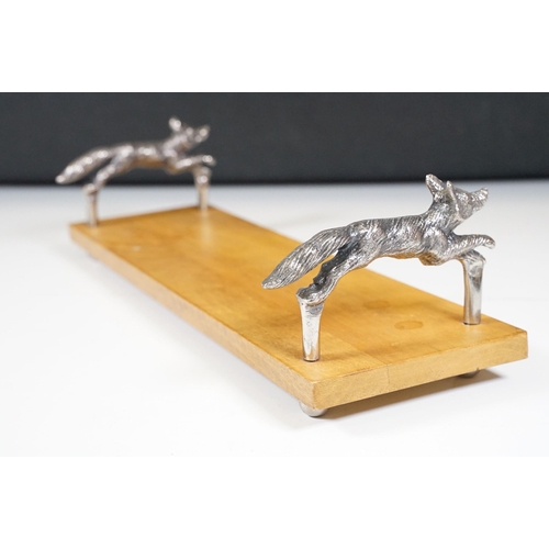 152 - Wooden bookstand with cast metal supports in the form of running foxes, on four ball feet, 44cm long