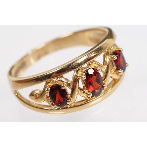 147 - 9ct gold and garnet three stone ring being set with three oval cut garnets in a pierced mount settin... 