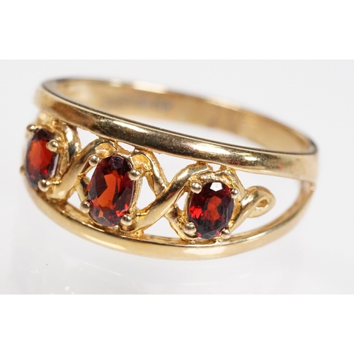 147 - 9ct gold and garnet three stone ring being set with three oval cut garnets in a pierced mount settin... 