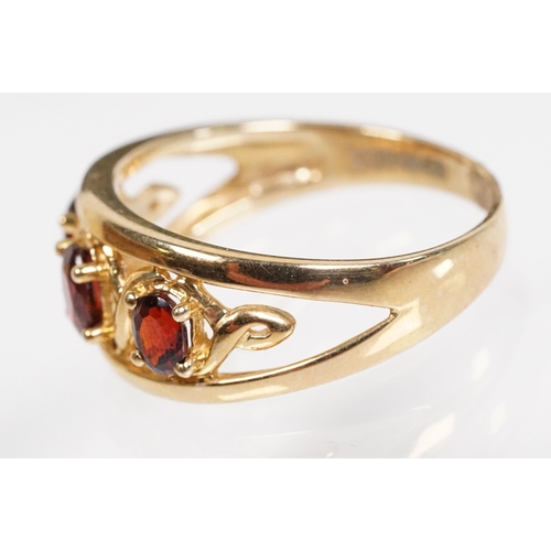 147 - 9ct gold and garnet three stone ring being set with three oval cut garnets in a pierced mount settin... 