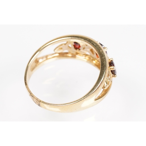147 - 9ct gold and garnet three stone ring being set with three oval cut garnets in a pierced mount settin... 
