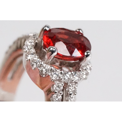 149 - 18ct gold red Andesine feldspar and diamond dress ring. The ring being set with an oval red a Andesi... 