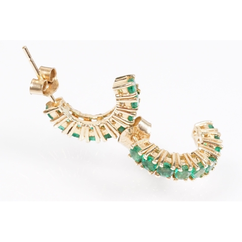 153 - Pair of 14ct gold and emerald half hoop earrings being set with nine round cut emeralds. Marked 14k.... 