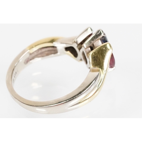 172 - 18ct gold, ruby and sapphire three stone ring. The ring being set with a marquise cut sapphire to ce... 