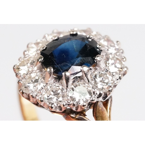 7 - 18ct gold sapphire and diamond halo ring. The ring being set with an oval mixed cut blue sapphire wi... 