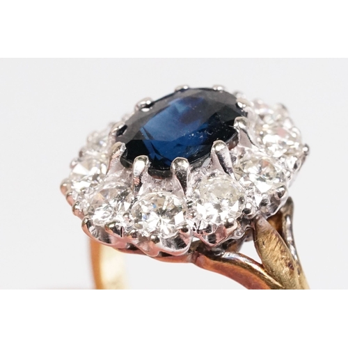 7 - 18ct gold sapphire and diamond halo ring. The ring being set with an oval mixed cut blue sapphire wi... 