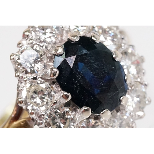 7 - 18ct gold sapphire and diamond halo ring. The ring being set with an oval mixed cut blue sapphire wi... 