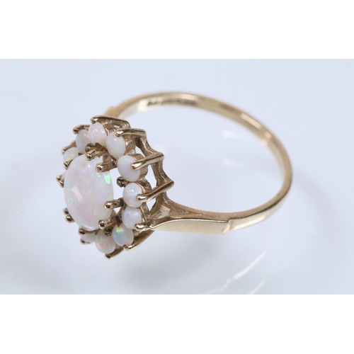 46 - 9ct gold and opal cluster ring. The ring being set with an oval opal cabochon to centre with a halo ... 