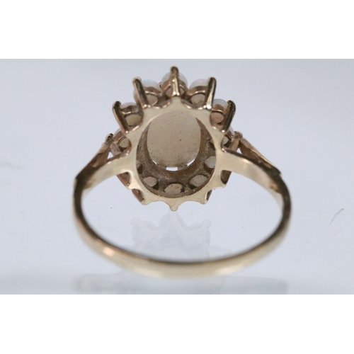 46 - 9ct gold and opal cluster ring. The ring being set with an oval opal cabochon to centre with a halo ... 
