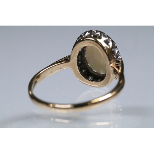 139 - 9ct gold, opal and diamond halo ring. The ring being set with an oval opal cabochon to the centre wi... 
