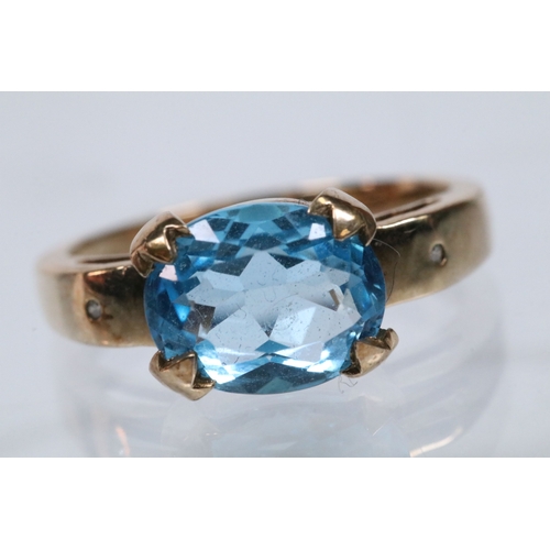 159 - 9ct gold and topaz dress ring set with an oval cut topaz flanked by two diamond accent stones. Hallm... 