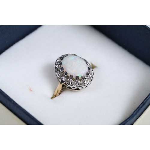 139 - 9ct gold, opal and diamond halo ring. The ring being set with an oval opal cabochon to the centre wi... 