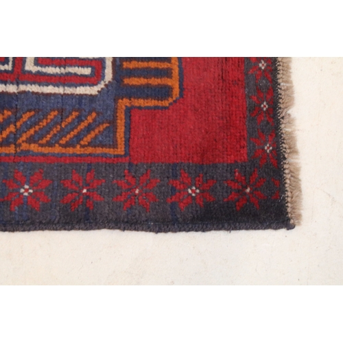 634 - Baluchi rug having a red ground with two geometric medallions to the central panel, 152cm x 88cm
